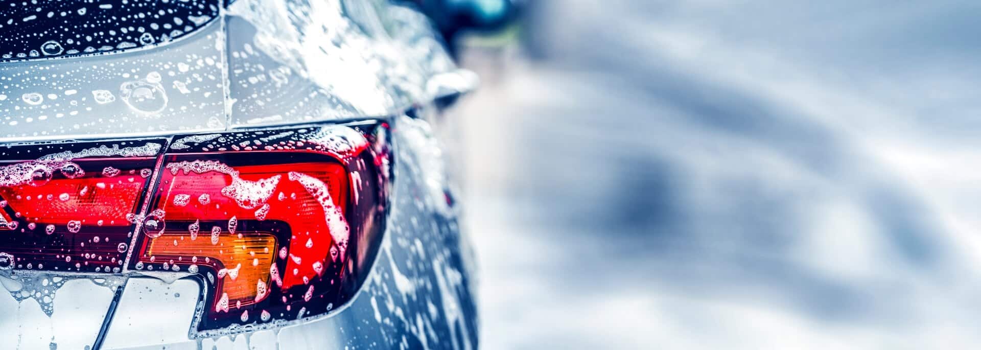 Backside of small sedan as it is being washed